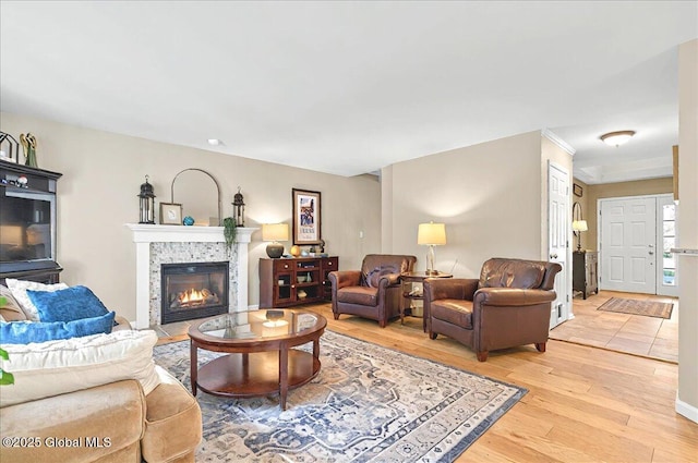 living room with a tiled fireplace and light wood-style flooring