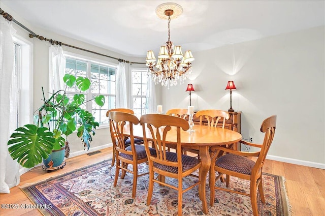 dining room featuring an inviting chandelier, baseboards, light wood-style floors, and visible vents