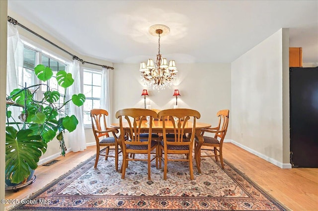 dining room featuring an inviting chandelier, baseboards, and light wood finished floors