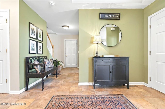 hallway with baseboards, stairs, and stone finish flooring