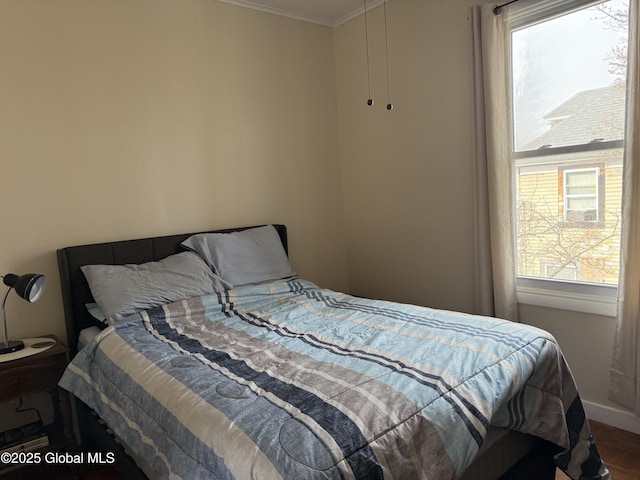 bedroom with baseboards, crown molding, and wood finished floors