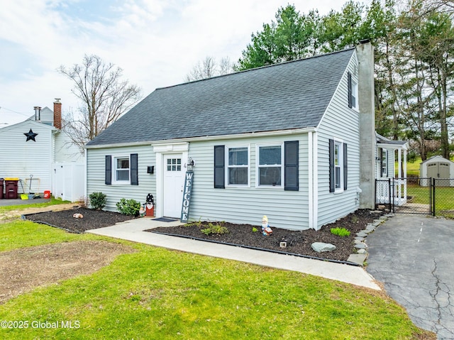 new england style home featuring a chimney, a gate, fence, and a front yard