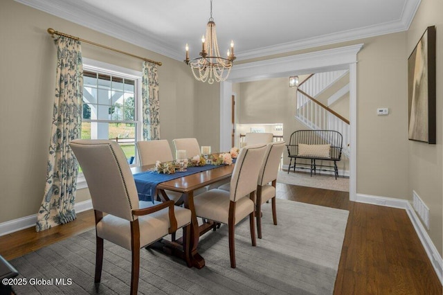dining area featuring visible vents, wood finished floors, baseboards, a notable chandelier, and ornamental molding
