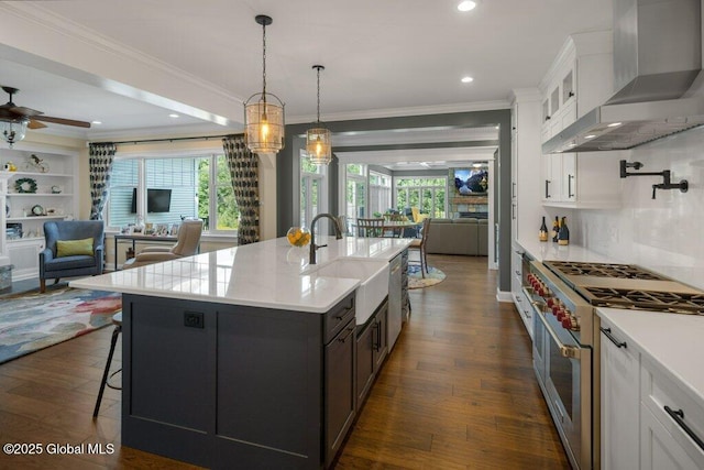 kitchen featuring open floor plan, dark wood-type flooring, wall chimney exhaust hood, a sink, and double oven range