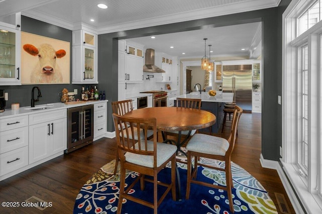 dining room with dark wood-style flooring, crown molding, a notable chandelier, wine cooler, and bar area