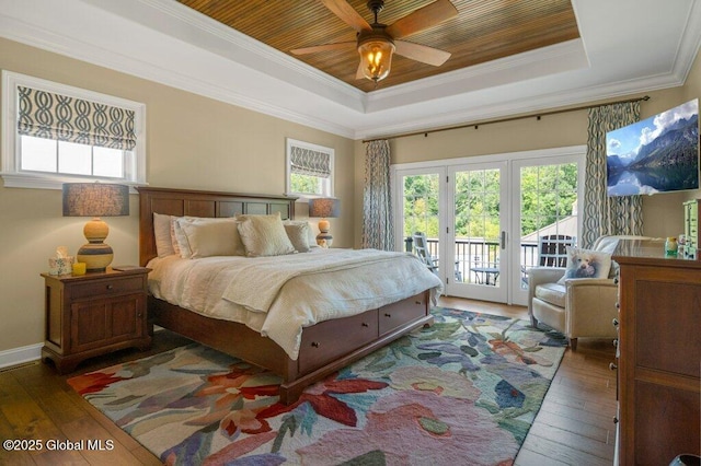 bedroom featuring access to outside, ornamental molding, a raised ceiling, and hardwood / wood-style floors