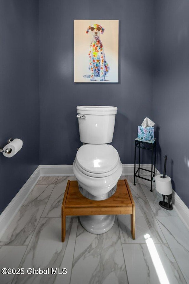 half bath with toilet, baseboards, and marble finish floor