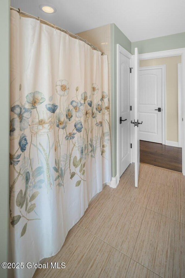 full bath with baseboards and a shower with shower curtain
