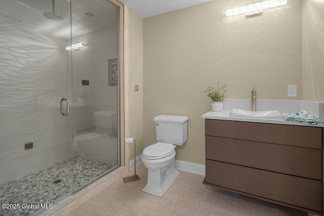 bathroom featuring a stall shower, vanity, tile patterned floors, baseboards, and toilet