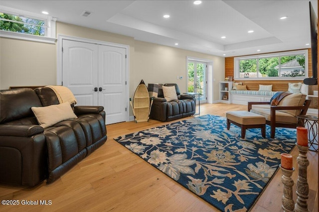 living area featuring visible vents, recessed lighting, wood finished floors, and a tray ceiling