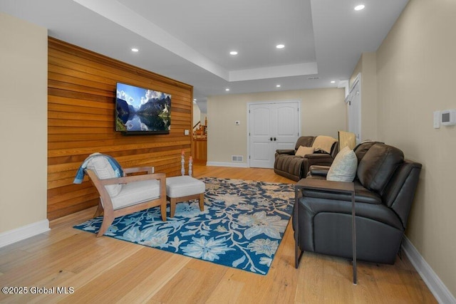 living room with visible vents, wood finished floors, baseboards, recessed lighting, and a raised ceiling