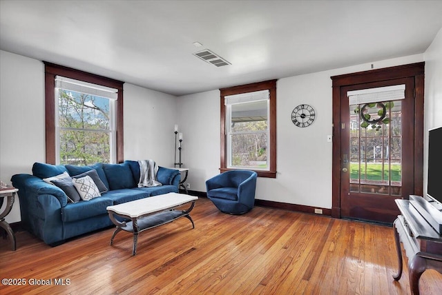 living area with visible vents, light wood-style floors, and a healthy amount of sunlight