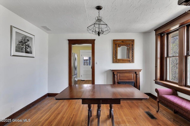 dining area with baseboards, a chandelier, a textured ceiling, and visible vents