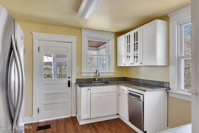 kitchen featuring glass insert cabinets, dark wood-type flooring, white cabinets, a sink, and stainless steel appliances