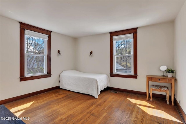 bedroom with baseboards, multiple windows, and wood finished floors