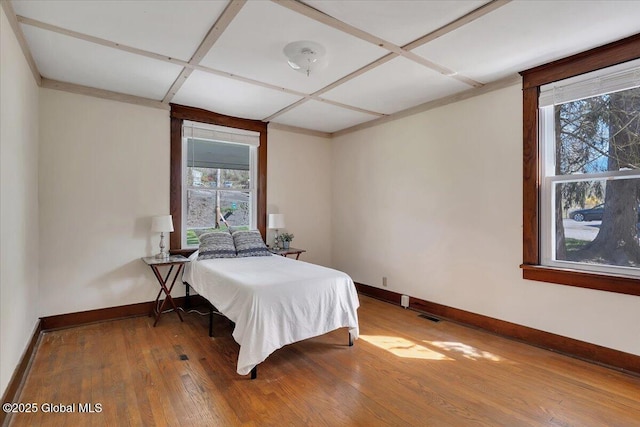 bedroom with baseboards, multiple windows, and wood finished floors