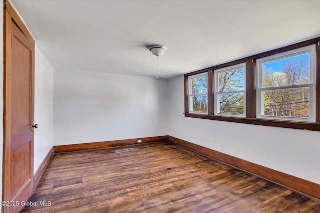 spare room featuring baseboards, dark wood finished floors, and visible vents