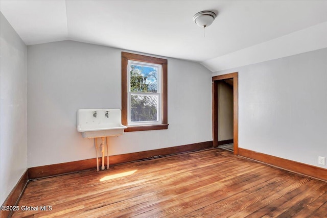 bonus room featuring light wood-style floors, baseboards, and vaulted ceiling