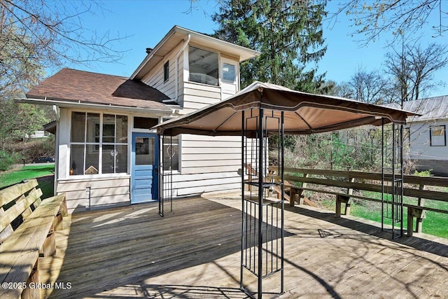 wooden deck featuring a gazebo, a sunroom, and a carport
