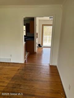 hallway featuring crown molding, baseboards, visible vents, and dark wood-style floors