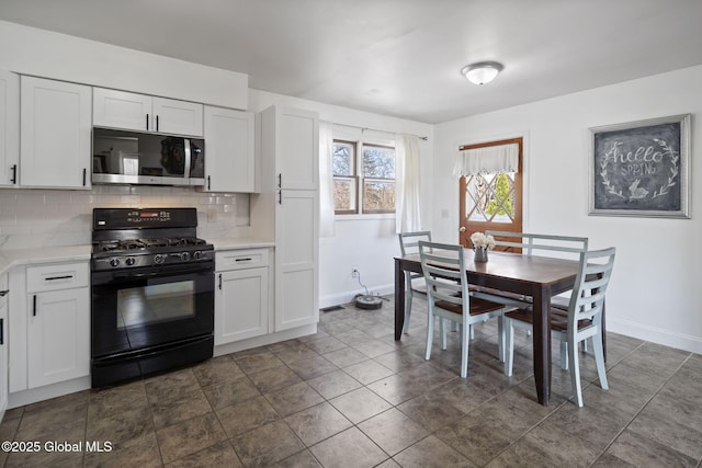 kitchen featuring black gas stove, light countertops, baseboards, and stainless steel microwave