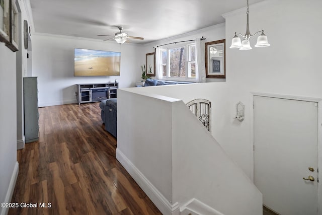 hall with baseboards, a chandelier, ornamental molding, and dark wood-style flooring