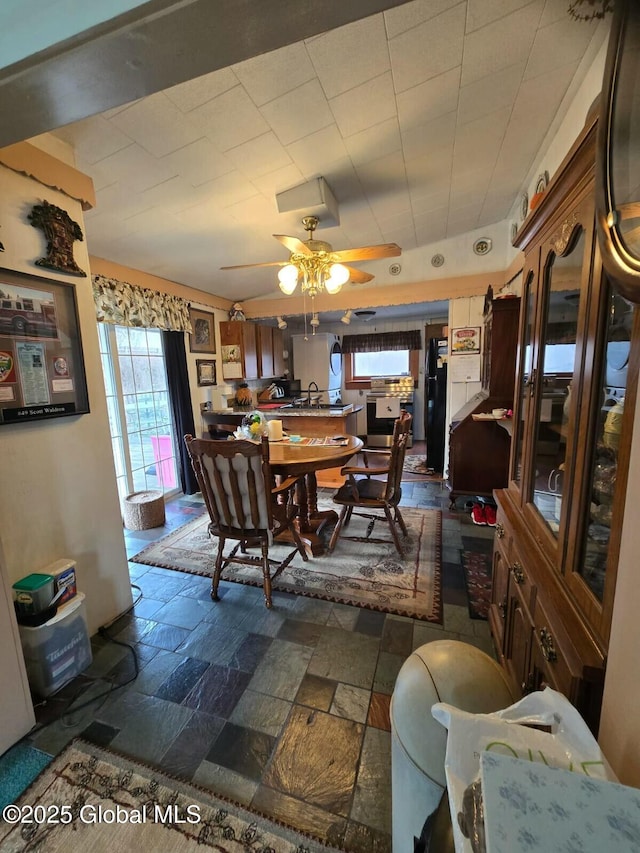 dining area featuring ceiling fan and stone finish floor