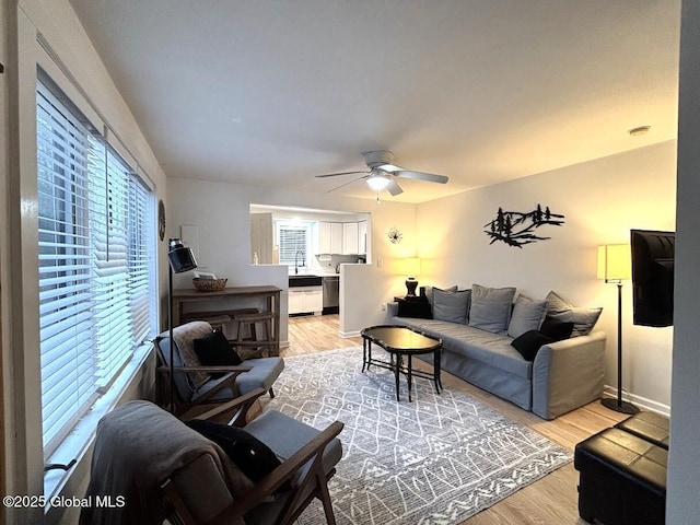 living room featuring baseboards, a ceiling fan, and light wood-type flooring