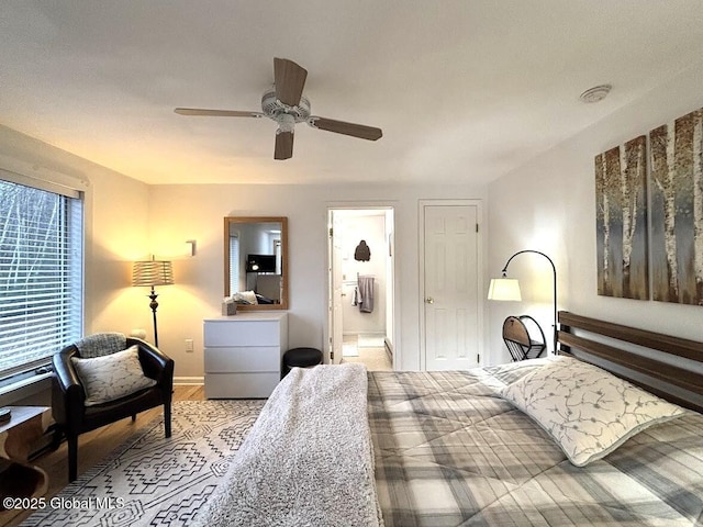 bedroom with baseboards, a ceiling fan, wood finished floors, and ensuite bathroom