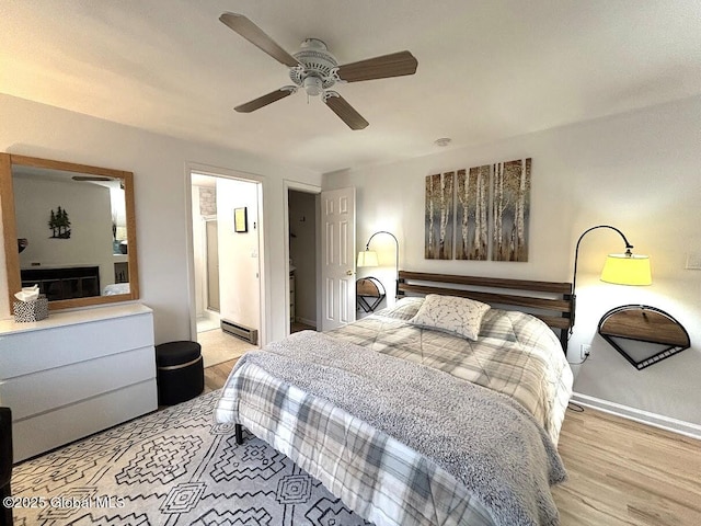 bedroom with light wood finished floors, ceiling fan, baseboards, and a baseboard heating unit
