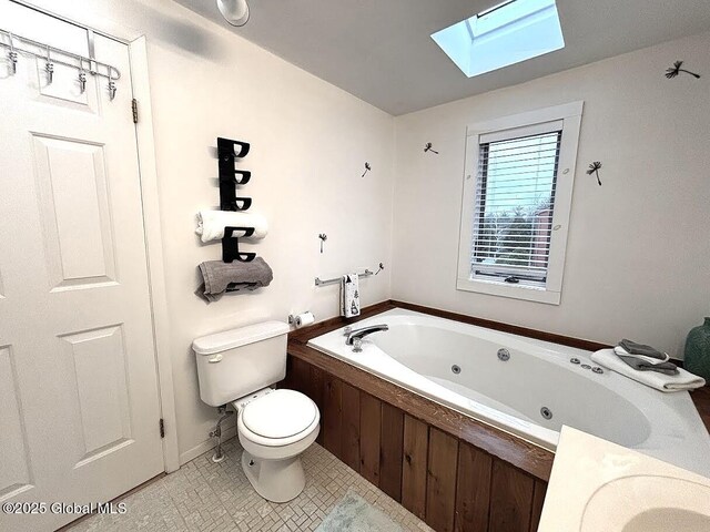 full bath featuring a skylight, a whirlpool tub, tile patterned flooring, and toilet