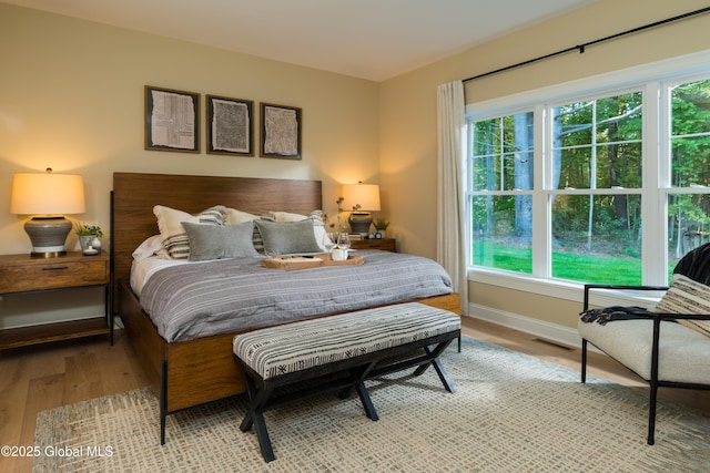 bedroom with light wood-style flooring, visible vents, and baseboards