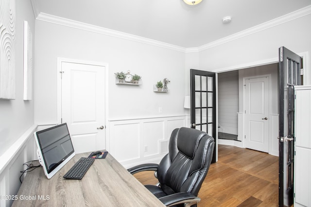 office area with crown molding, wainscoting, a decorative wall, and wood finished floors