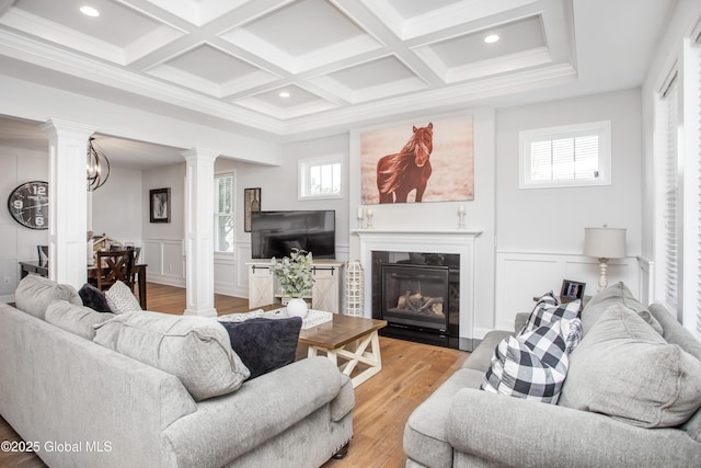 living room with a fireplace with flush hearth, decorative columns, light wood finished floors, and a decorative wall