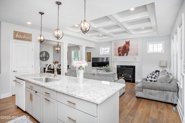 kitchen with a sink, light wood-style flooring, recessed lighting, decorative columns, and a fireplace with flush hearth