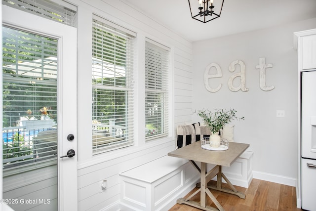 dining area with baseboards, a notable chandelier, and light wood-style flooring