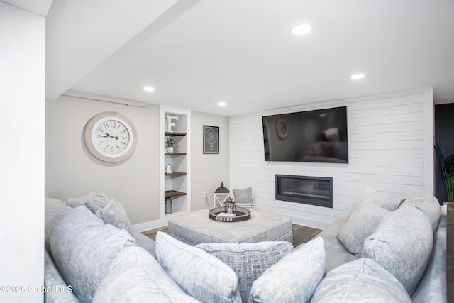 living area featuring wood finished floors, baseboards, recessed lighting, built in shelves, and a large fireplace
