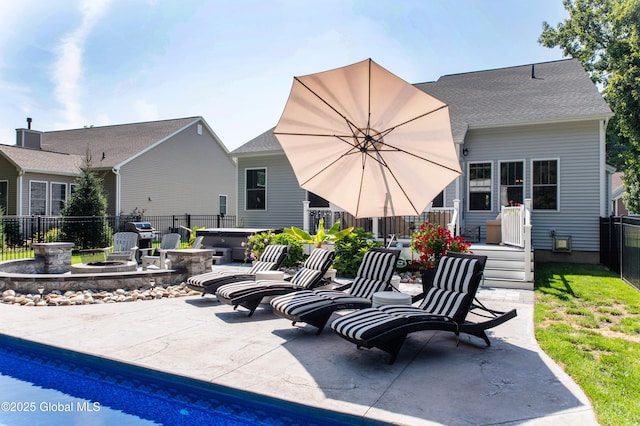 back of property with a patio area, a hot tub, fence, an outdoor fire pit, and a shingled roof