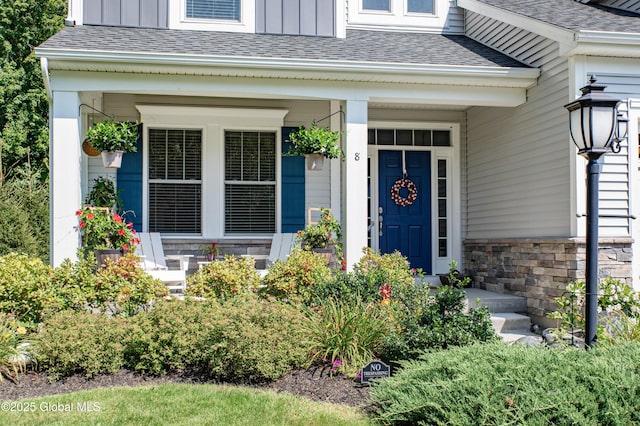 property entrance with board and batten siding, stone siding, covered porch, and roof with shingles