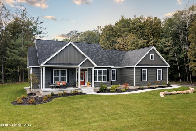 craftsman house featuring covered porch, a front yard, and roof with shingles