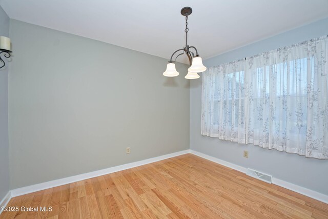 87 Dorchester Ave, Bethlehem, NY 12158 - spare room with wood finished floors, visible vents, baseboards, and a notable chandelier