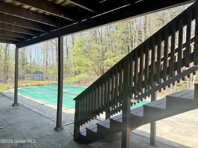 view of patio featuring fence, a storage shed, a covered pool, and an outbuilding