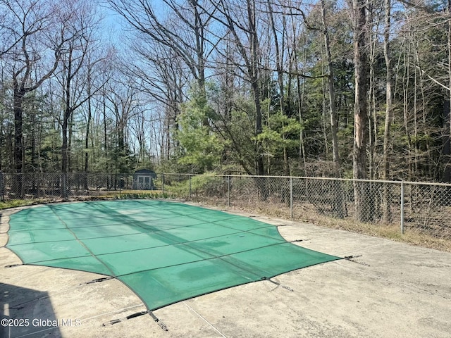 view of swimming pool with a patio, a fenced in pool, a fenced backyard, and a shed