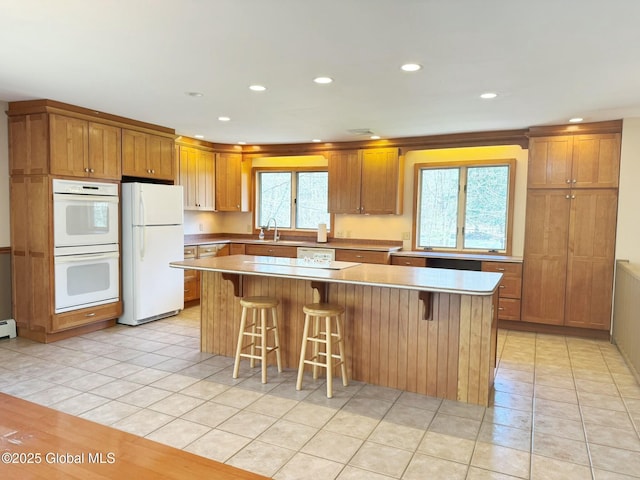 kitchen featuring a wealth of natural light, white appliances, a kitchen island, and a sink