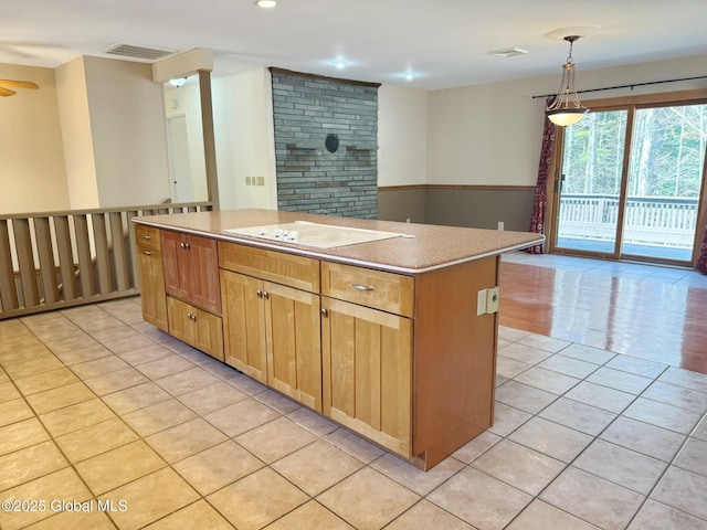 kitchen with white electric stovetop, hanging light fixtures, light tile patterned floors, a center island, and visible vents