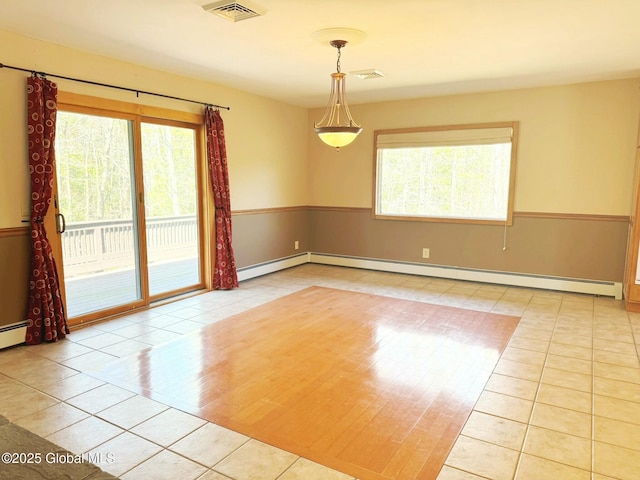 spare room with tile patterned floors, visible vents, a healthy amount of sunlight, and a baseboard heating unit