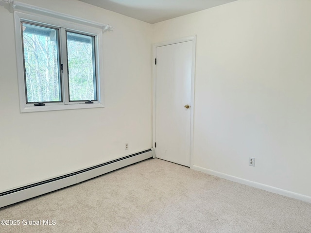 spare room with baseboard heating, baseboards, and light carpet