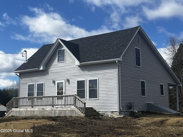 back of house with roof with shingles and a deck