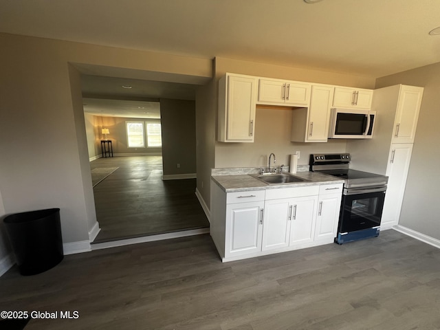 kitchen featuring baseboards, white microwave, dark wood-style floors, a sink, and stainless steel electric range oven