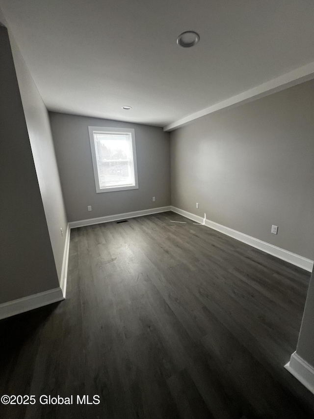 empty room featuring dark wood-style flooring and baseboards